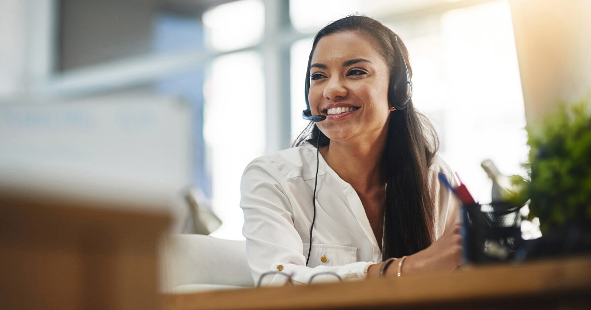 Customer service woman smiling while on the phone in office setting.